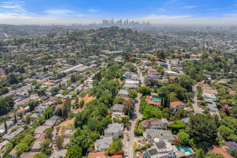 Aerial view of suburban homes and trees with the Los Angeles Skyline in the distance.