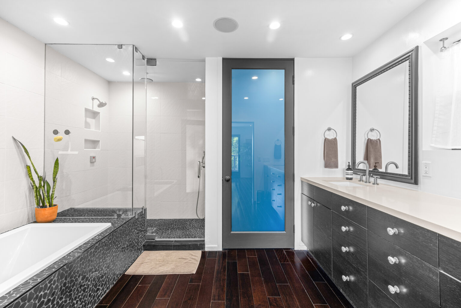 a clean bathroom with a marble bath and wooden floors.