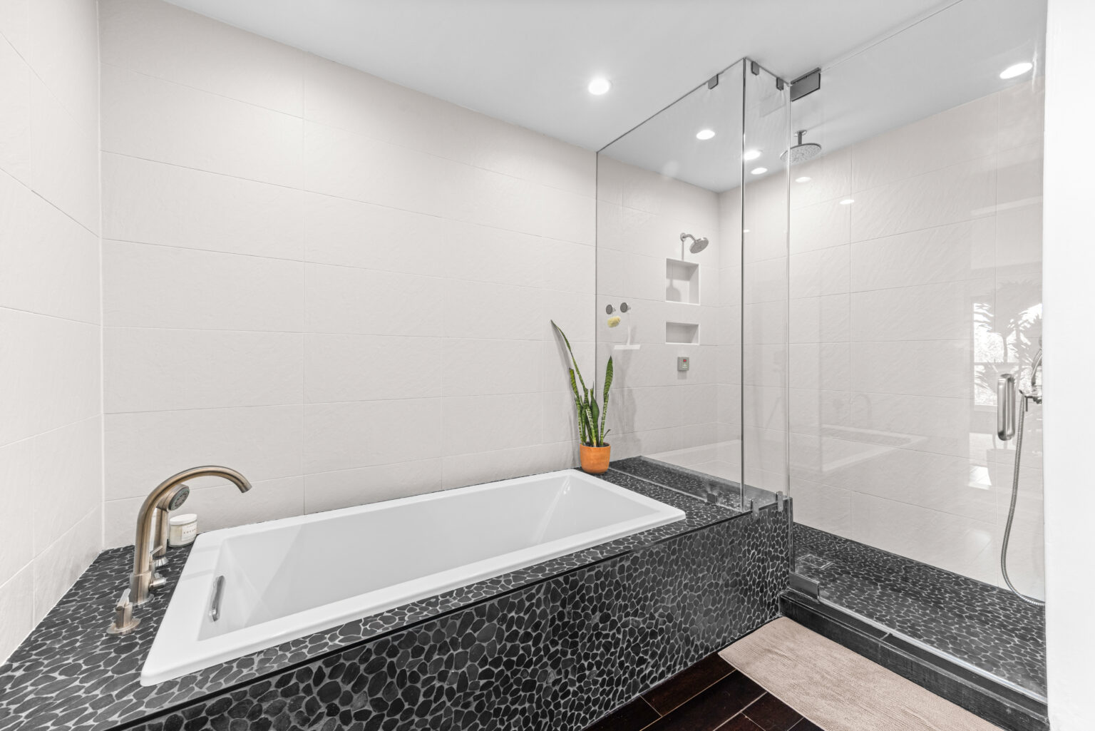 Modern bathroom with bathtub, glass shower, and tiled surround