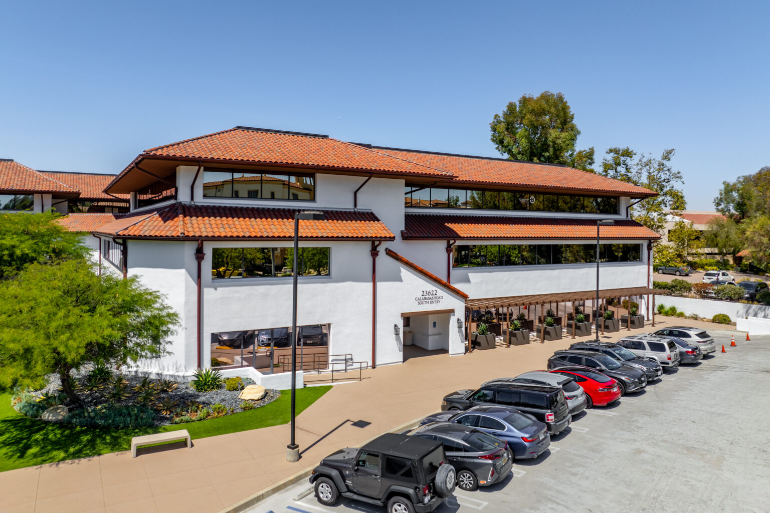 Office building exterior with red roof and parked cars