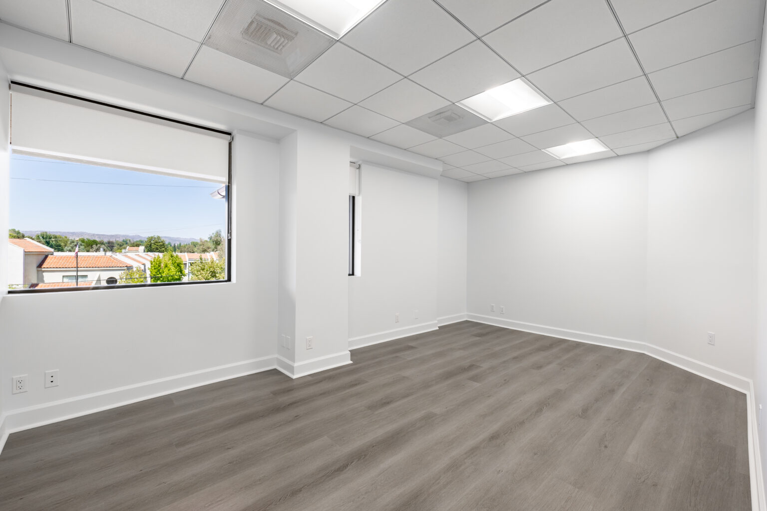 Another empty bright office with vinyl flooring and large windows