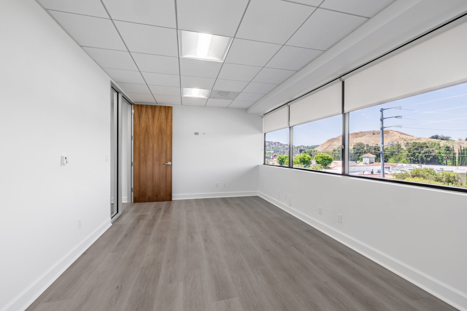 Empty office with wood flooring and large windows