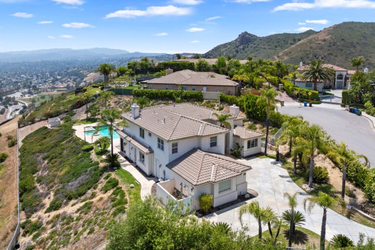 Angled view of home exterior with pool, hills in background