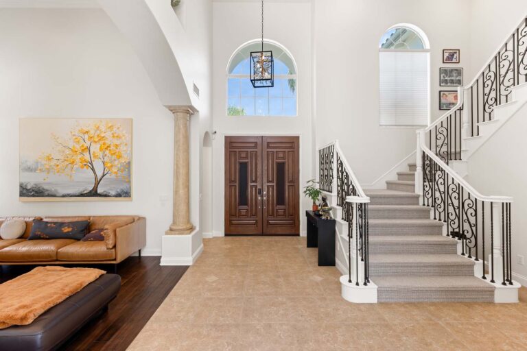 Foyer view with staircase, arched window, and double entry doors