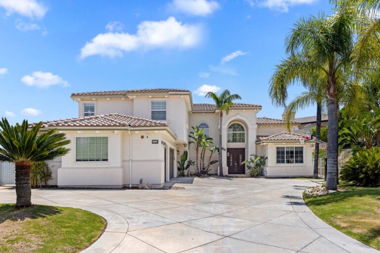 Angled front exterior with stone driveway and arched entry