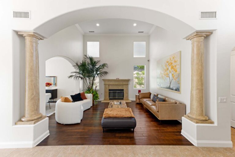 Living room with fireplace, archway, and seating under high ceiling
