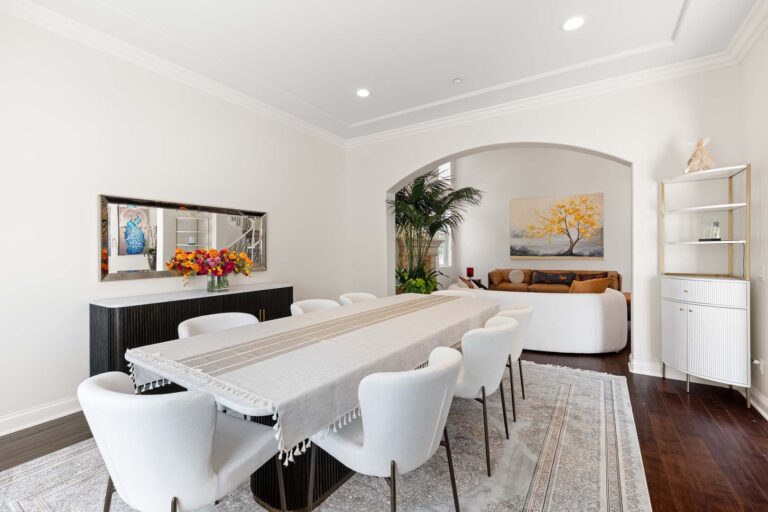 Dining area with white chairs, table, and archway