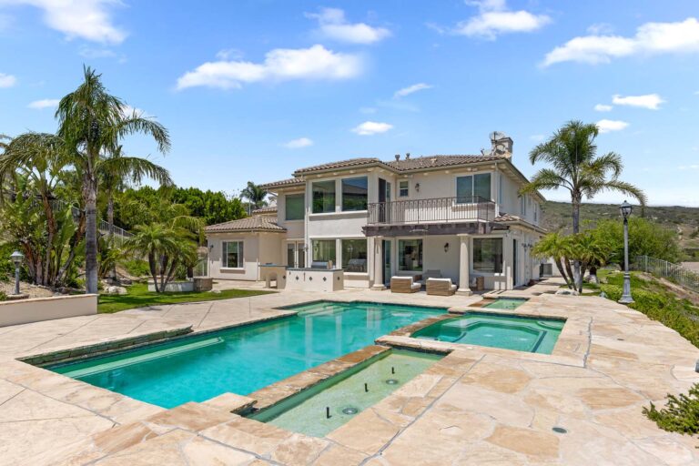 Back exterior of house with pool deck and palm trees