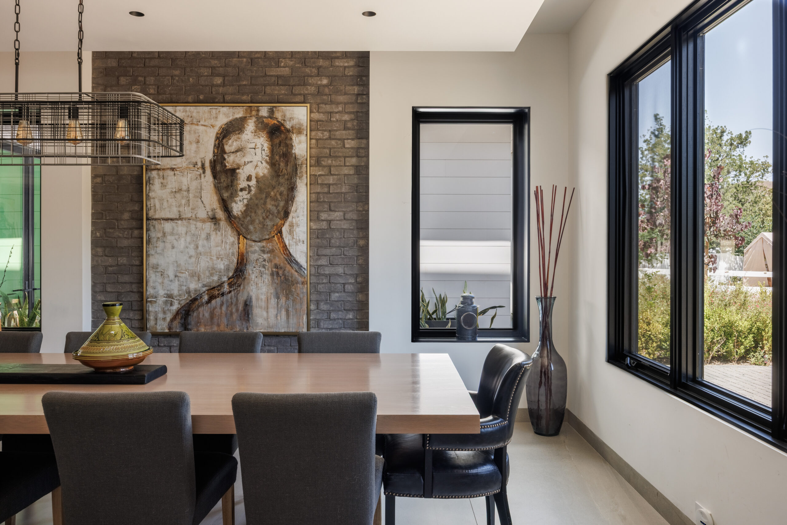 Long dining table near large windows with outdoor views in a bright open space.